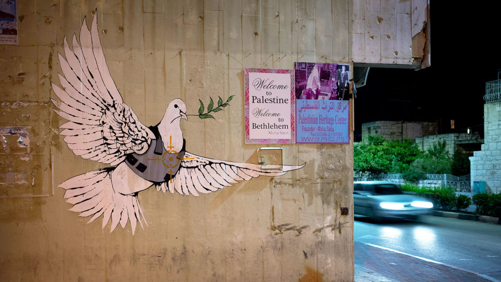 Bethlehem heute: 
Die Friedenstaube ist im Visier eines Scharfschützen, sie braucht eine Panzerweste – Graffiti des britischen Streetart-Künstlers Banksy, etwa 300 ­Meter entfernt vom Kontrollposten der Mauer in Bethlehem (Aufnahme aus dem Jahr 2015). | © Michael Meier