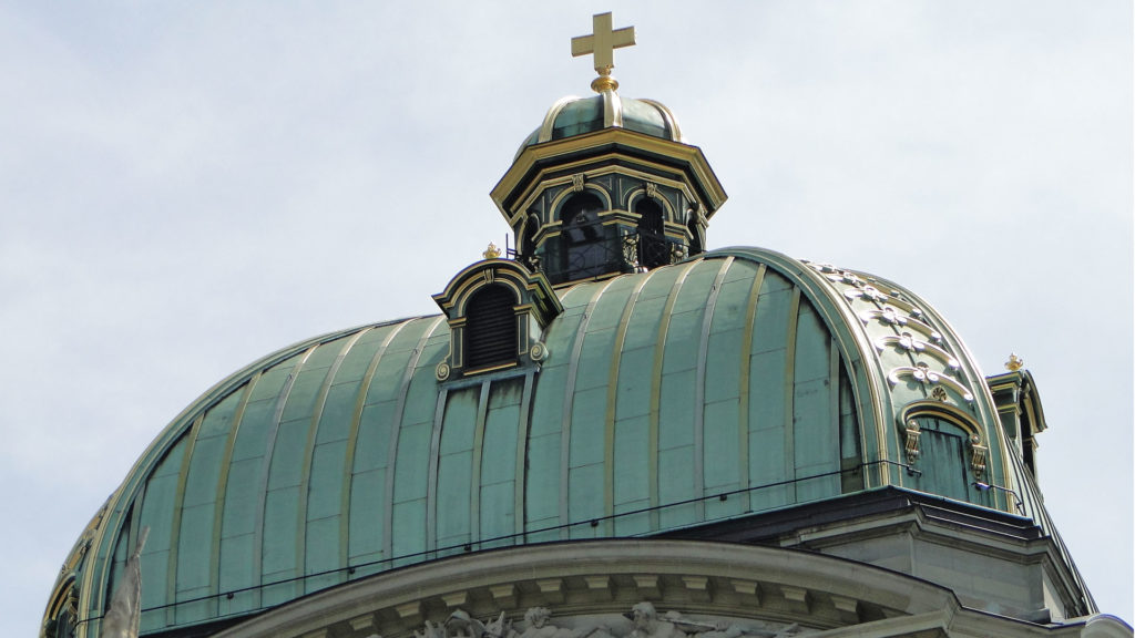 Die von einem vergoldeten Schweizerkreuz gekrönte Kuppel des Bundeshauses in Bern: Hier fallen wichtige politische Entscheide. | © wikimedia, Nikolai Karaneschev