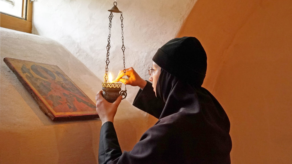 Äbtissin Archontia entzündet eine Kerze vor einer Ikone in der Krypta des Klosters Beinwil. | © Vera Rüttimann