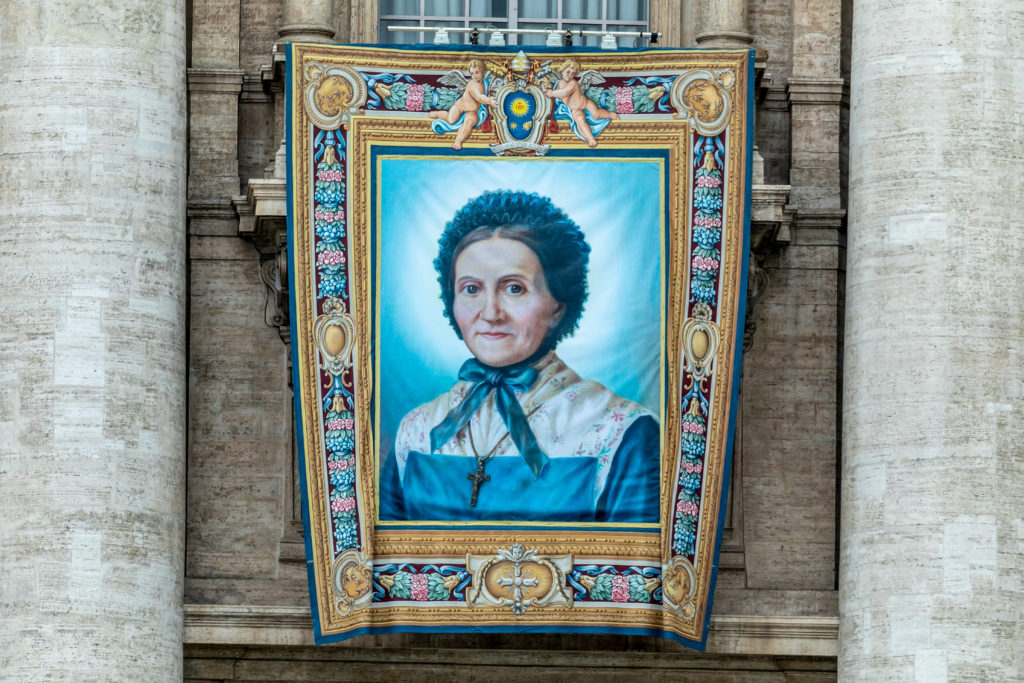 Transparent mit einer Darstellung von Marguerite Bays, Mitglied des Dritten Ordens des heiligen Franziskus, an der Fassade des Petersdoms im Vatikan. | © KNA-Bild