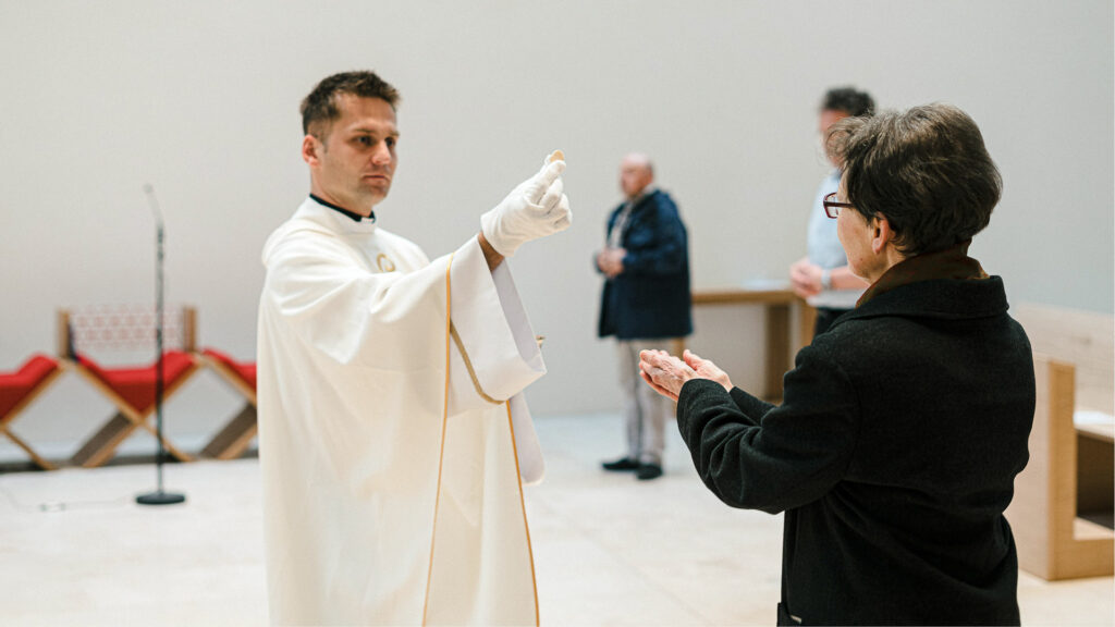 Propsteikirche Leipzig, 20. April: Ein Kaplan mit Handschuh spendet einer Frau die Kommunion. | © kna-bild.de