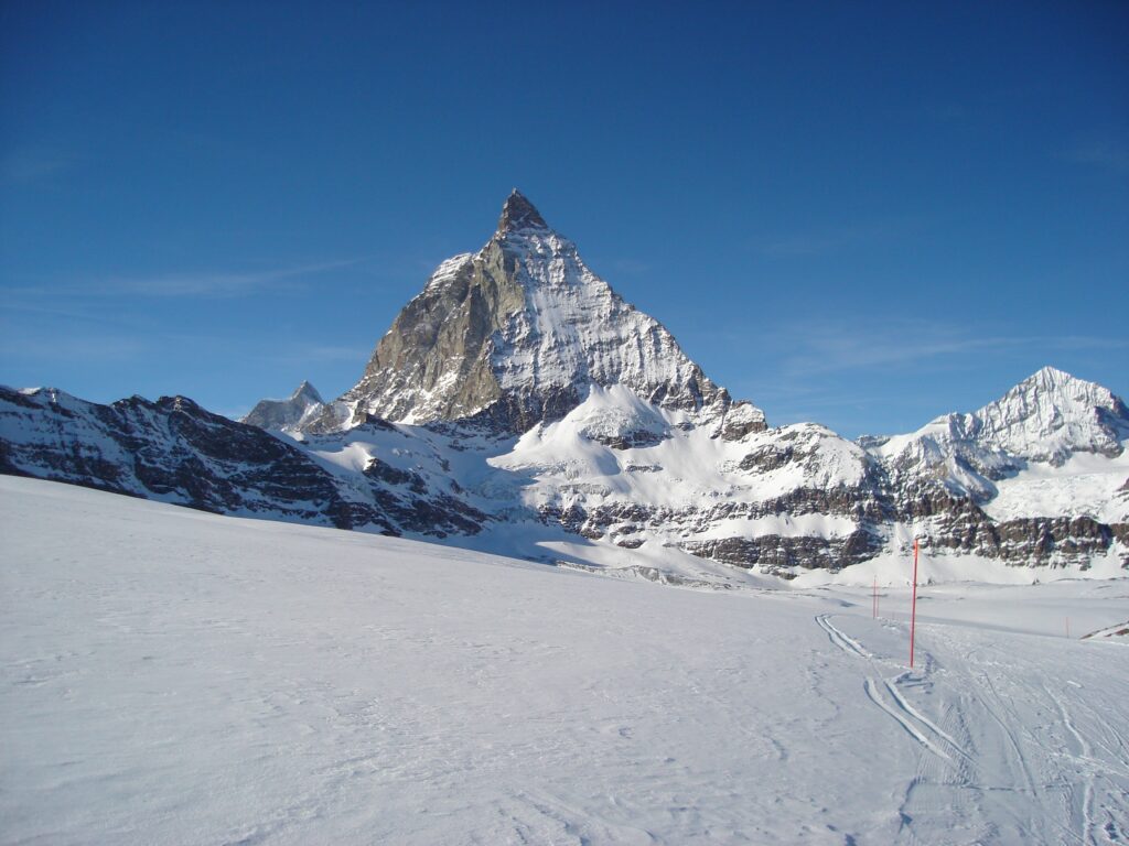 Das ist der Gipfel, den alle sehen wollen: das majestätisch über Zermatt thronende Matterhorn. Allerdings ist es hier nicht in der klassischen Ansicht von Norden her zu sehen, sondern von Osten her. Dafür ist der Hörnligrat (rechts) gut erkennbar. Der winterliche Schnee überdeckt, dass auch am schönsten Berg der Welt der Zahn der Zeit und vor allem der Klimaerwärmung nagt. Der heutige internationale Tag der Berge will die Gefährdung der Bergwelt durch die Klimakrise in den Fokus rücken. | © Markus Vogt 