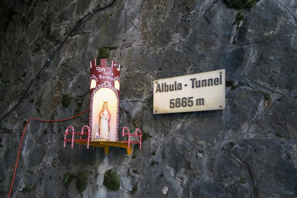 Der Legende nach wurde Barbara, deren Gedenktag auf den 4. Dezember fällt, durch einen sich öffnenden Felsen geschützt. Sie ist deshalb zur Patronin der Bergleute und Tunnelbauer geworden. In vielen Tunnelportalen finden sich Barbaraschreine, so auch am Nordeingang des Albulatunnels in Preda. | © Kecko/wikimedia