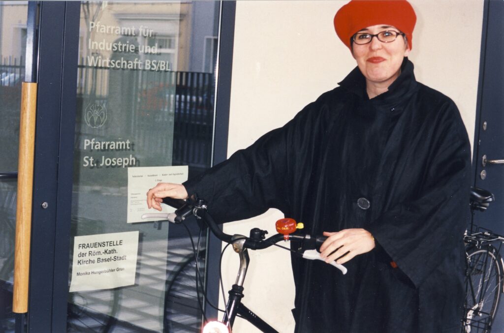 Mit Hut und Velo: Monika Hungerbühler vor dem Eingang zum Büro der damaligen Frauenstelle der Römisch-Katholischen Kirche Basel-Stadt (Januar 2003).  | © Archiv kh