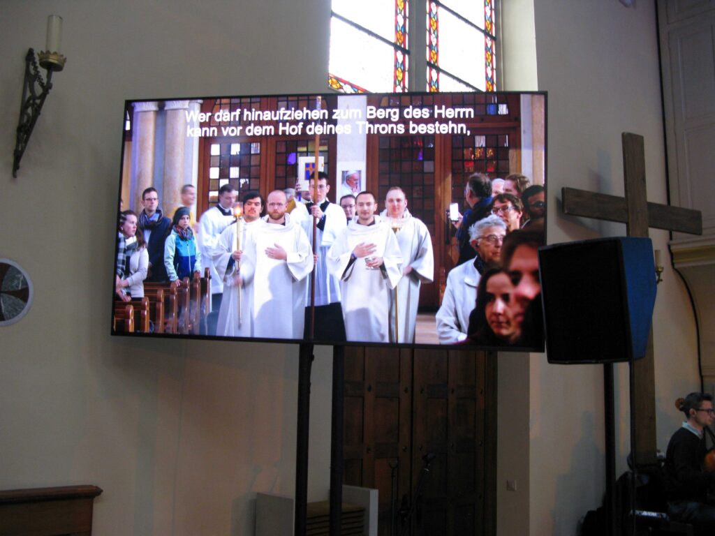 Auf grossen Bildschirmen war die Liturgie in allen Teilen des Kirchenschiffs zu verfolgen, zudem wurden die Liedtexte eingeblendet. | © Christian von Arx