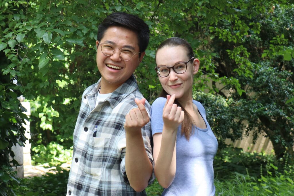 Eine typische Handgeste aus Südkorea: Die Finger bilden ein kleines Herz. Musung Mun (li., mit Redaktorin Leonie Wollensack, re.) möchte sich in seinem Heimatland für eine gerechtere und solidarischere Gesellschaft einsetzen. | © Mission 21, Evangelisches Missionswerk Basel